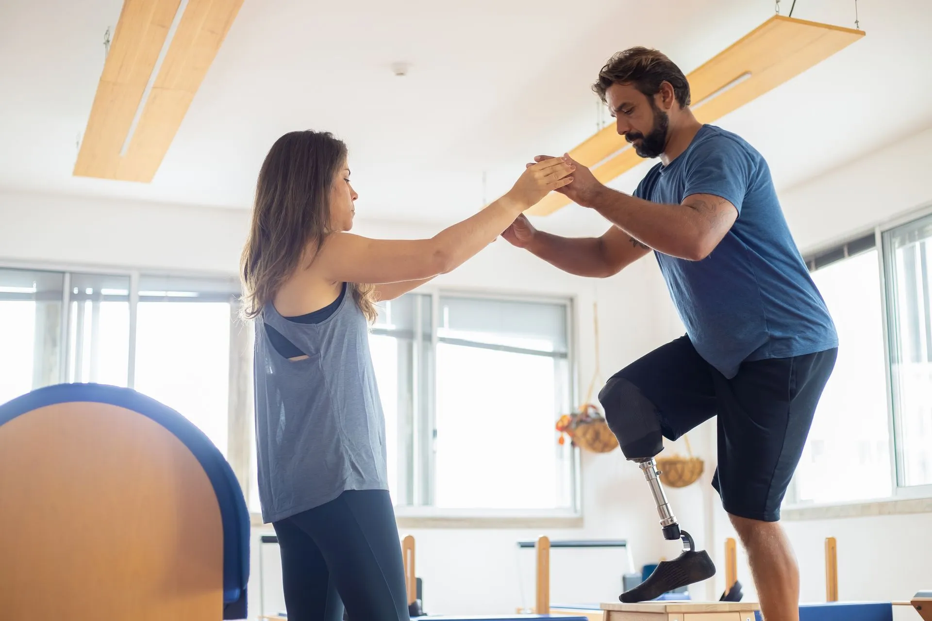 A physical therapist guiding a patient through a balance exercise in a bright gym