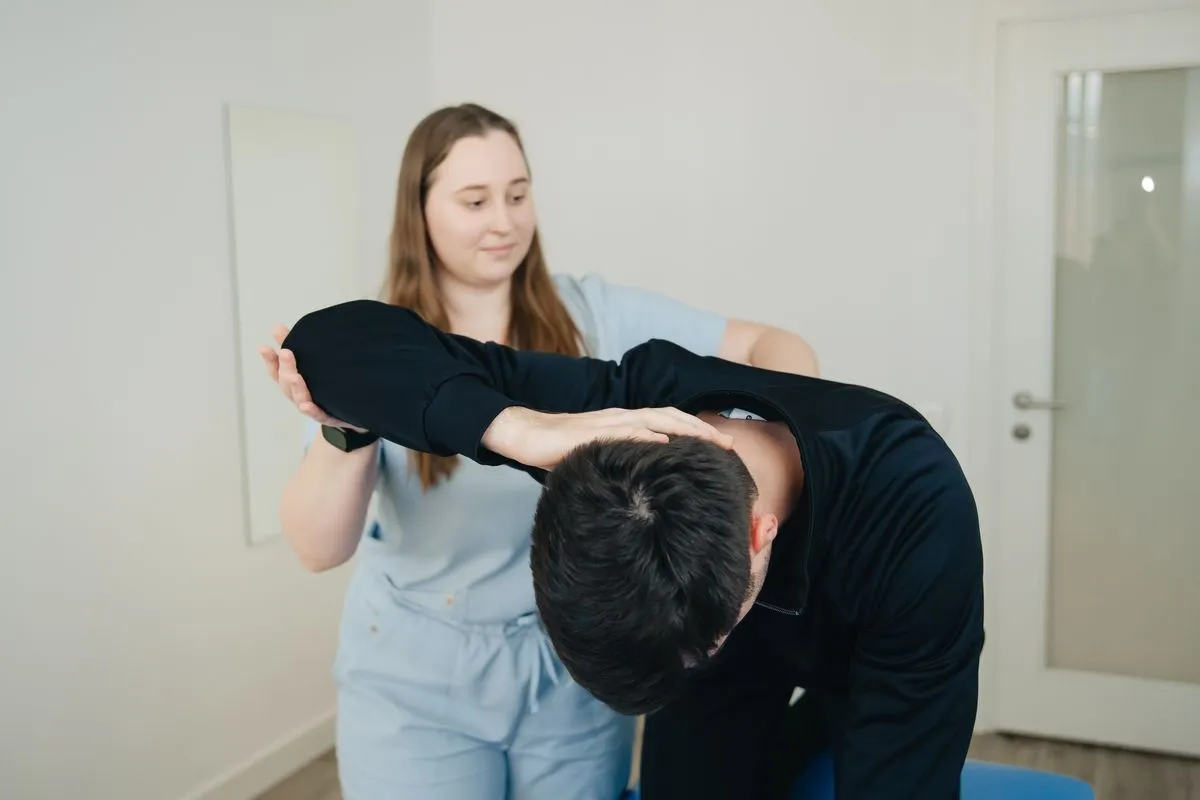 A physical therapist assessing a patient's shoulder and neck movement