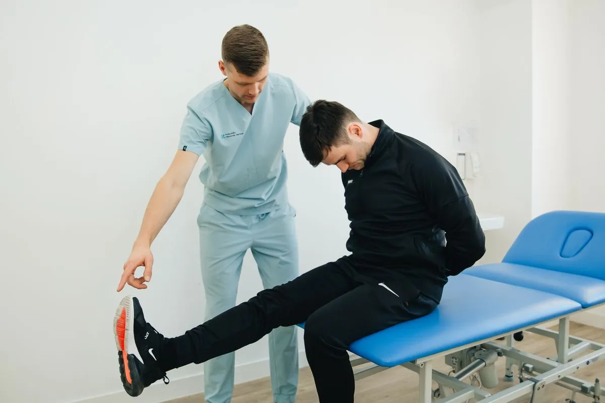 A physical therapist guiding a patient through a leg raise on a treatment table